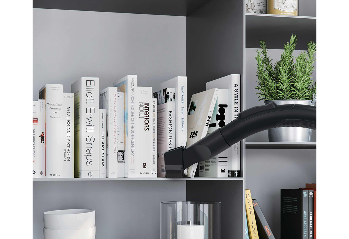 Απεικονίζεται το ακροφύσιο να καθαρίζει σε βιβλία στο ράφι.